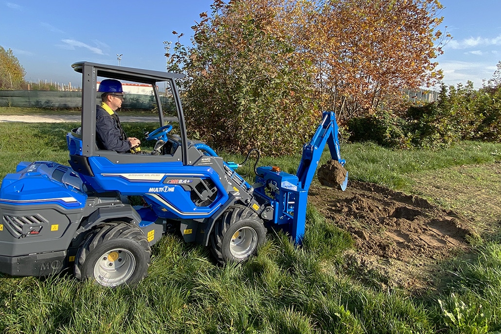 a man operating with a radio controlled backhoe to move soil
