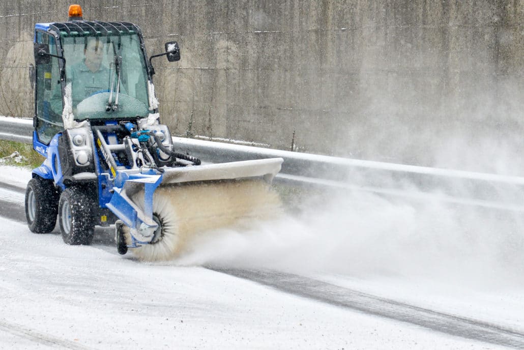 mini loader 2 series with rotary broom cleaning a snowy street