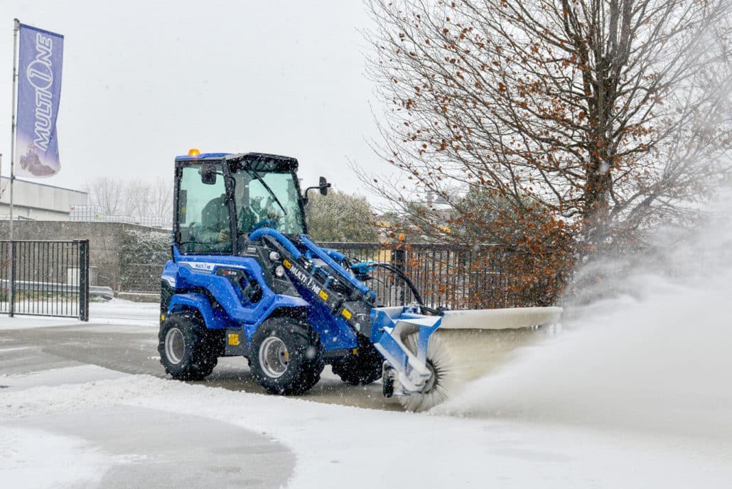 a mini loader 6 series with rotary broom cleaning a snowy parking