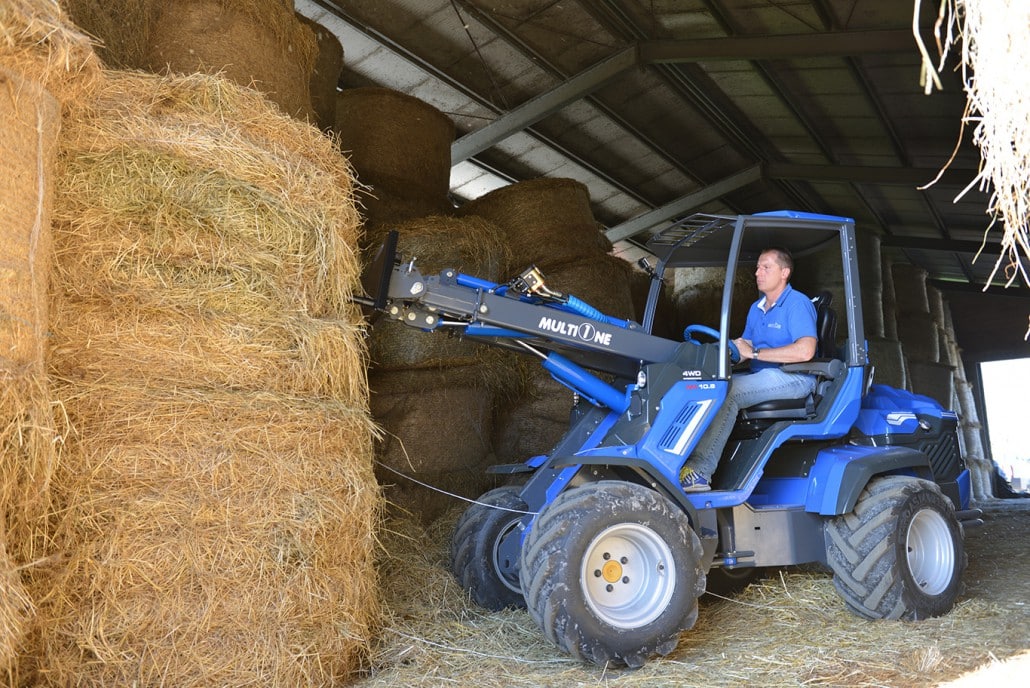 man using a bale fork to lift a big hay bale