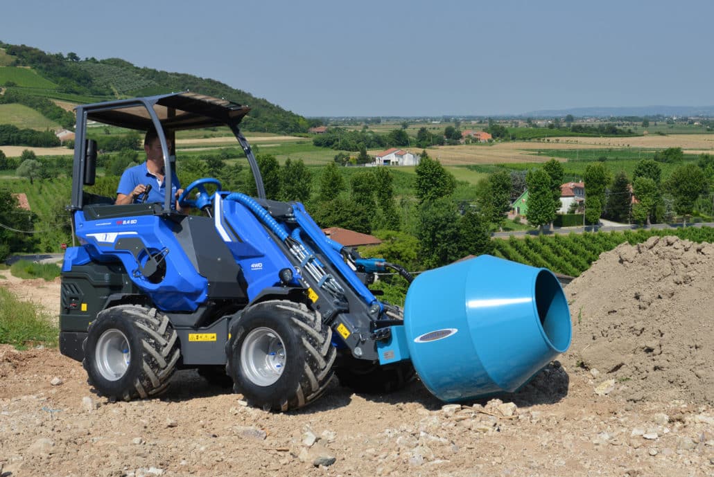 man using a multione cement mixer in a bucolic setting
