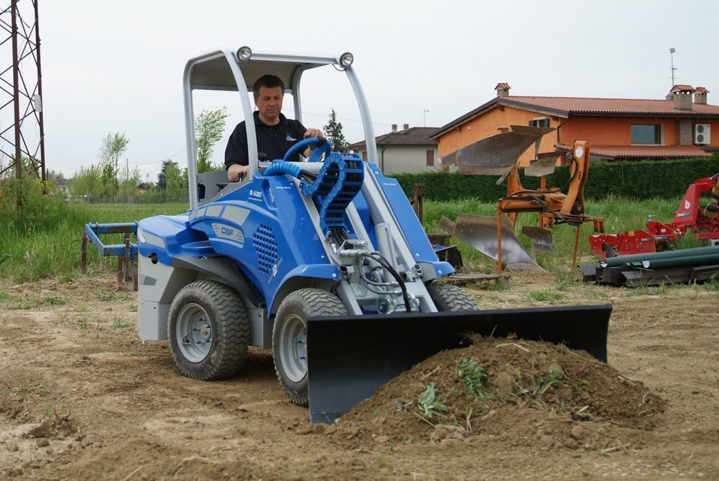 man using a dozer blade to move soil