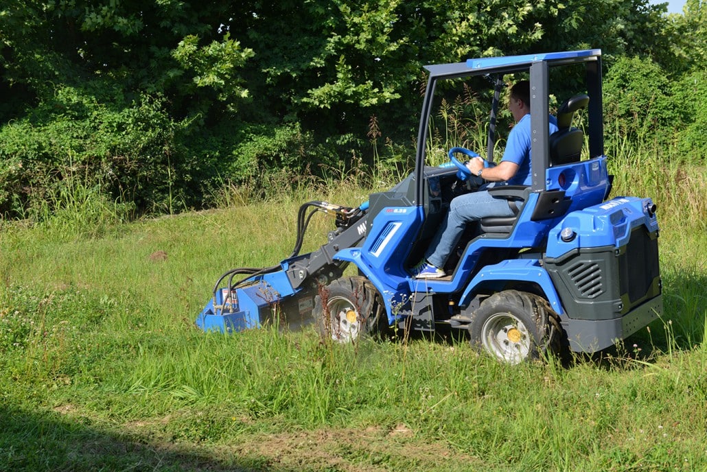 flail mower cutting grass in a garden, seen from behind