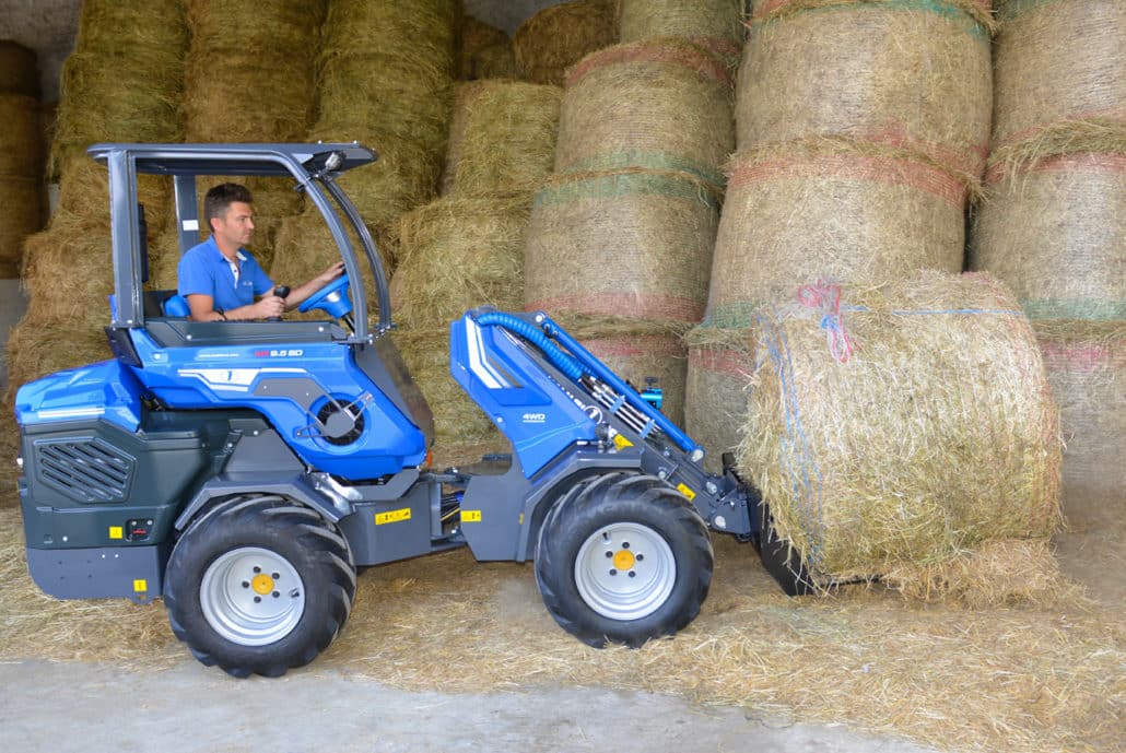 manure fork moving a hay bale