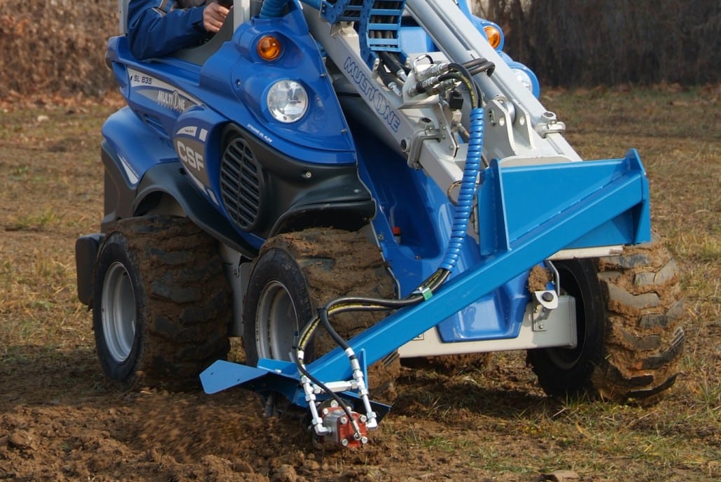 power plough working on soil, front view
