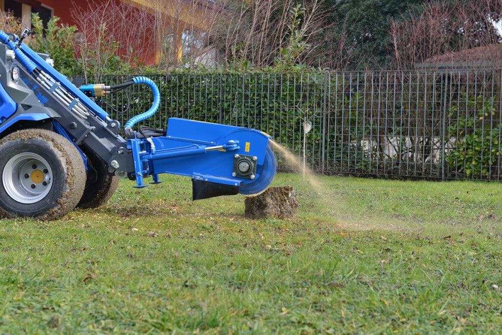 swing stump grinder in action on a grass field