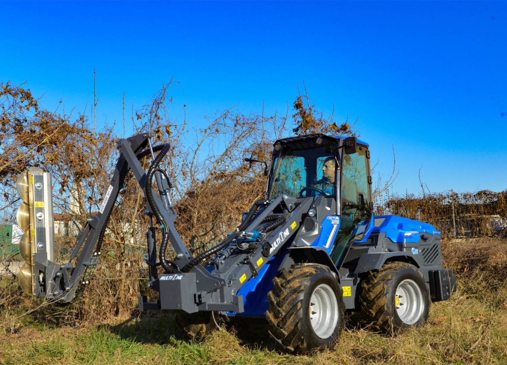 man using an articulated side arm to cut dry hedges